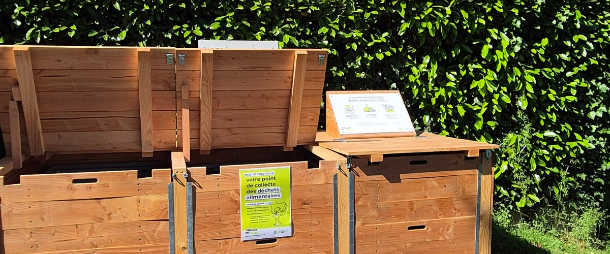 Deux des trois bacs en bois sont ouverts pour déposer les déchets alimentaires. 